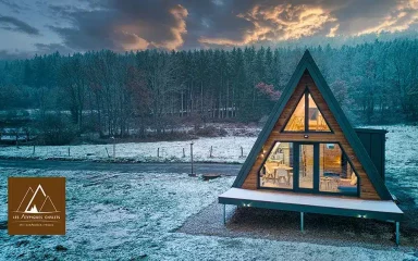 Vue des Atypiques Chalets de Gérardmer entourés de nature verdoyante dans les Vosges.