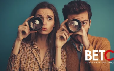 Deux personnes, un homme et une femme, regardant à travers des objectifs d'appareils photo, symbolisant la curiosité et l'exploration. Logo de BETC en bas à droite.