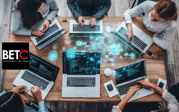 Équipe de travail collaborant sur des ordinateurs portables dans une agence digitale BETC.