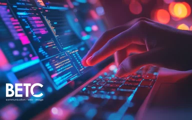 Main tapant sur un clavier illuminé, représentant le travail numérique dans une agence digitale.