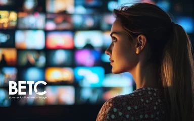 Jeune femme observant un écran numérique avec le logo de BETC en premier plan, représentant l'agence de communication.