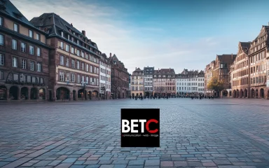 Place centrale du Grand Est avec des bâtiments historiques et logo de BETC Communication, agence digitale.