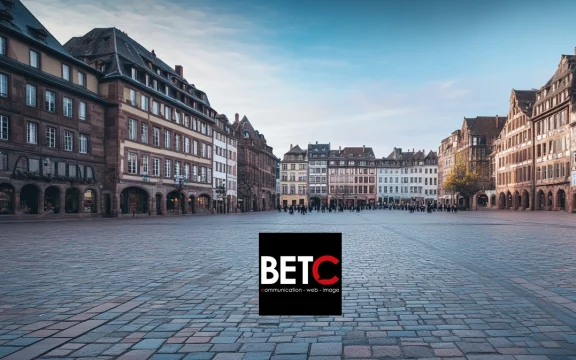 Place centrale du Grand Est avec des bâtiments historiques et logo de BETC Communication, agence digitale.