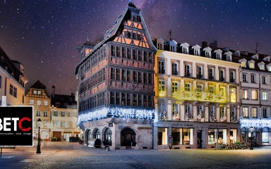 Place de la Cathédrale à Strasbourg illuminée la nuit, avec la Maison Kammerzell en avant-plan, reflétant l'histoire locale et l'importance de la visibilité en ligne.