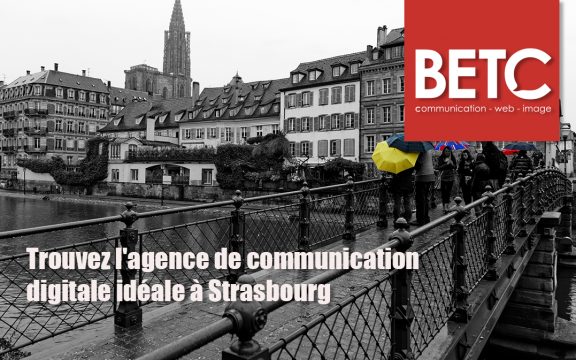 Vue de Strasbourg avec la cathédrale en arrière-plan, un pont animé et des passants tenant des parapluies colorés, illustrant l'importance d'une agence de communication digitale locale comme BETC.
